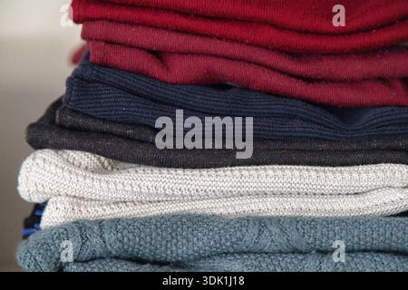 Pile de pulls en tricot pliés de différentes couleurs soigneusement disposés sur une étagère, mettant en évidence les textures confortables et le rangement organisé de la garde-robe Banque D'Images