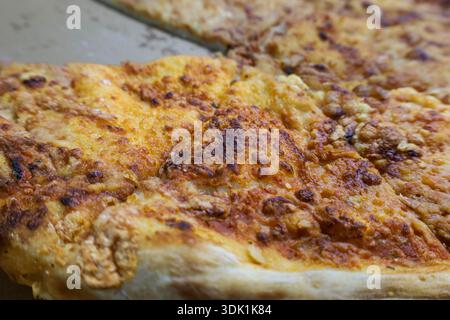 Gros plan détaillé d'une tranche de pizza au fromage avec fromage fondu et croûte croustillante, adaptée aux concepts alimentaires et de restauration rapide. Banque D'Images