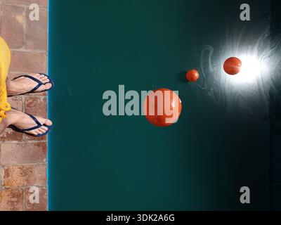 Boules rouges tombant dans l'eau de la piscine. Banque D'Images