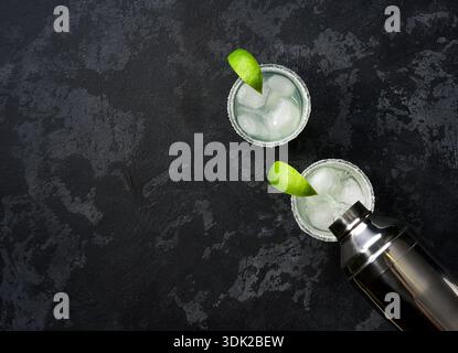 Le barman verse un cocktail de margarita dans un verre, mise au point sélective sur un fond noir, espace de copie pour le texte. Banque D'Images