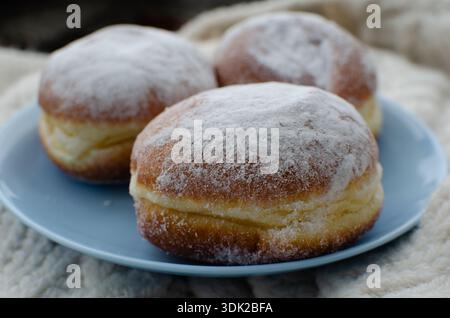 Délicieux beignets avec du sucre en poudre sur une assiette, vue rapprochée de l'angle Banque D'Images