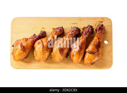 Pilons de poulet grillé sur une planche à découper, vue de dessus. Cuisses de poulet croustillantes frites sur une planche à découper. cuisses de poulet grillées sur une planche à découper isolat Banque D'Images
