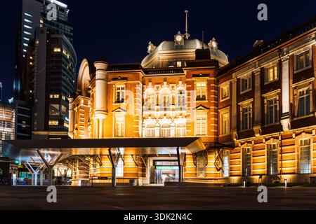 Tokyo, Japon - 3 août 2024 : illumine la gare de Tokyo et les gratte-ciel environnants sous un ciel nocturne bleu foncé, mettant en valeur le mélange de l'arc historique Banque D'Images