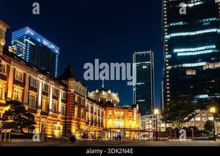 Tokyo, Japon - 3 août 2024 : illumine la gare de Tokyo et les gratte-ciel environnants sous un ciel nocturne bleu foncé, mettant en valeur le mélange de l'arc historique Banque D'Images