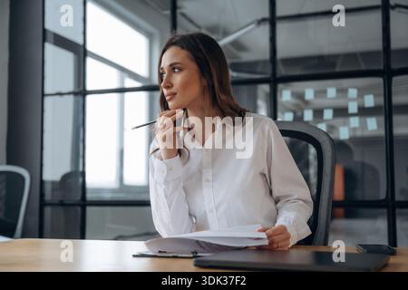 Assis et réfléchi. Une belle femme est au bureau. Banque D'Images