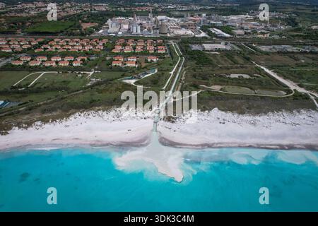 Vue aérienne de sable blanc rencontrant des eaux turquoises, contrastant avec des complexes industriels et des zones résidentielles, Rosignano Solvay, Toscane, Italie. Banque D'Images