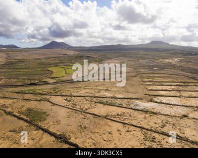 Vue aérienne de champs arides gravés de lignes sombres sous un vaste ciel, montagnes lointaines faisant écho à la beauté du paysage, la Oliva, Fuerteventu Banque D'Images