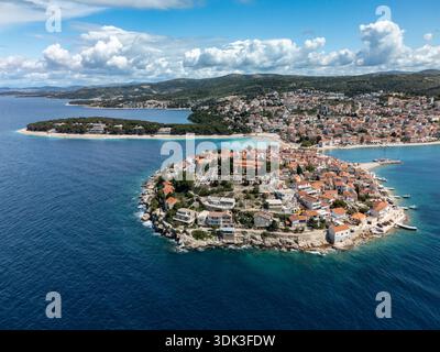 Vue aérienne des toits en terre cuite de la vieille ville en cascade vers l'Adriatique turquoise, la péninsule embrassée par la côte croate, Primošten, C. Banque D'Images