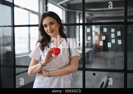 Coeur de jouet rouge dans coeur de cardiologue. Femme médecin est dans le bureau. Banque D'Images