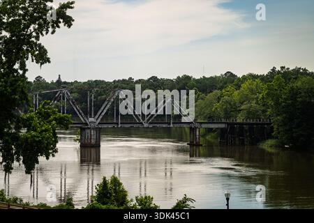 Un vieux pont ferroviaire rouillé se dresse silencieusement au-dessus des eaux sombres et calmes de la rivière Flint à Bainbridge, en Géorgie. La filte lumineuse brumeuse de l'après-midi Banque D'Images