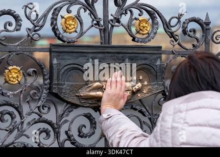 Femme touchant le relief en bronze de Saint Jean de Nepomuk sur le pont Charles, Prague, République tchèque Banque D'Images