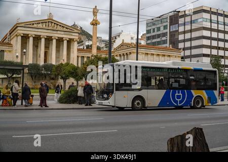 Académie d'Athènes, Akadimía Athinón. Bâtiment néoclassique de Theophil Hansen, contrastant avec un bus public électrique moderne à zéro émission à Athènes. Banque D'Images