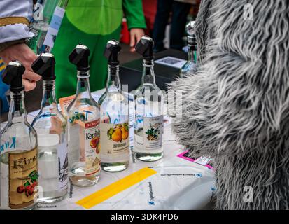 Zug, Suisse - 1er mars 2025 : une personne en costume à fourrure attend un verre d'eau de vie de fruits locaux versé lors du défilé du carnaval d'hiver de Fasnacht Banque D'Images