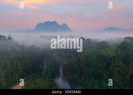 Découvrez la beauté sereine du parc national de Khao Sok tandis que la brume matinale couvre la végétation luxuriante et les montagnes majestueuses de Surat Thani, en Thaïlande. A t Banque D'Images
