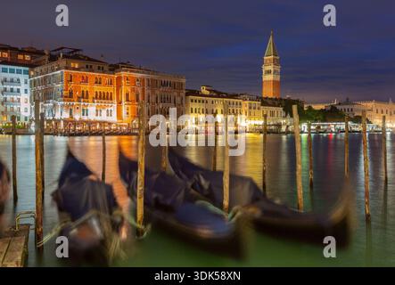 Les gondoles flottent sur le Grand canal de Venise, en Italie, la nuit, avec des bâtiments illuminés et le Campanile San Marco en arrière-plan. Banque D'Images
