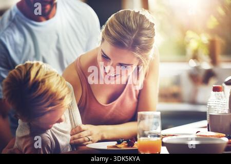 Heureux, maman et chatouillant enfant dans la cuisine, le petit déjeuner ou les personnes avec la nutrition à la maison, l'amour et le jeu. Rire, garçon et nourriture saine pour la famille Banque D'Images