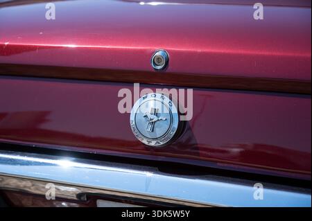 Plan de détail arrière d'une Ford Mustang 289 classique de 1ère génération, mettant en valeur l'emblème du cheval et le chrome sur la malle Bordeaux. Banque D'Images