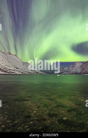 Vue sur les aurores boréales vertes éthérées dansant au-dessus des eaux calmes et glacées, reflétant les montagnes enneigées dans un spectacle à couper le souffle, Ersf Banque D'Images