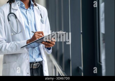 Écrire les informations dans le bloc-notes. Vue rapprochée du médecin en pelage à l'intérieur. Banque D'Images