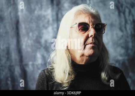 Portrait d'une femme caucasienne de soixante-dix ans portant des lunettes de soleil Banque D'Images