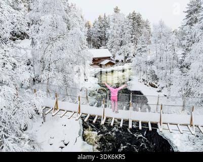 Femme joyeuse sur un pont glacé au-dessus des rapides froids Banque D'Images