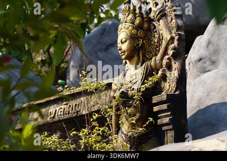 Une fresque en pierre d'un Bouddha doré dans le jardin Banque D'Images