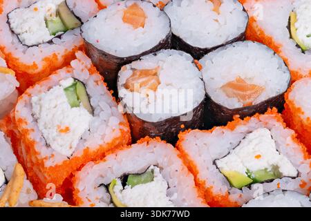 Des rouleaux de sushi bien rangés disposés sur une assiette en flatlay minimaliste, des motifs répétés de riz, nori et tobiko créent une texture forte et une symétrie, un dos propre Banque D'Images