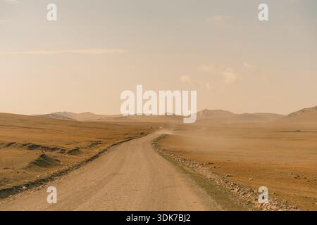 Un chemin de terre traversant un paysage aride et vallonné. Photo de haute qualité Banque D'Images