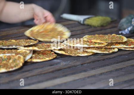 Lahmacun turc fraîchement cuit dans une boulangerie traditionnelle : pain plat mince et croustillant au four de pierre garni de viande hachée, de légumes et d'herbes sur un Woode Banque D'Images