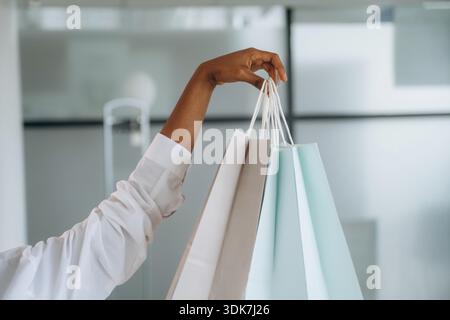 Vue rapprochée de la main de la femme qui tient des sacs à provisions à l'intérieur. Banque D'Images