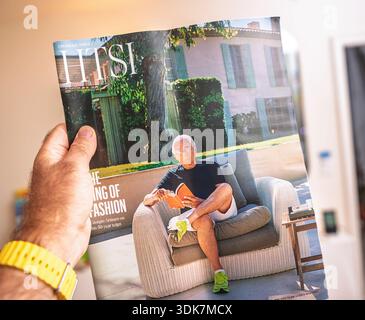 Paris, France - 4 septembre 2025 : Hand Holding Financial Times How to Spend It magazine mettant en vedette Giorgio Armani assis à l'extérieur sur une chaise en osier Reading bo Banque D'Images