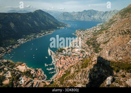 Vue aérienne des toits en terre cuite descendant vers la baie scintillante, encadrée par des montagnes majestueuses, Kotor, municipalité de Kotor, Monténégro. Banque D'Images