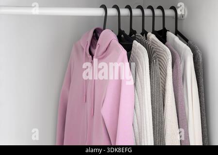 Sweat à capuche rose doux suspendu dans une garde-robe blanche minimale. Mode style de vie décontracté. Banque D'Images