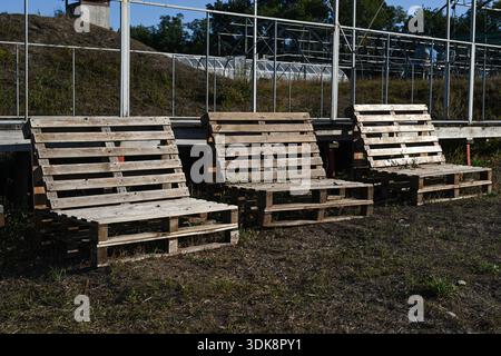 Chaises longues de palette disposées sur le sol extérieur, palettes en bois utilisées comme meubles pour le cadre extérieur rustique, chaises de bricolage dans la campagne avec ciel bleu Banque D'Images