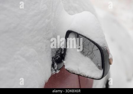 Gros plan extrême du rétroviseur latéral d'une voiture complètement enfoui dans une épaisse neige blanche.   Banque D'Images