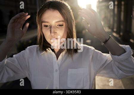 Flux d'esprit conscient, vagues d'esprit attentionné, gros plan de femme en chemise blanche avec les mains levées se déplaçant dans l'air de la nature vague-semblable à l'habitude de Everythin Banque D'Images