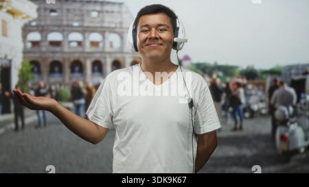 L'homme tient la paume vers le haut portant un casque devant le bâtiment du colisée avec la foule floue et les scooters ; voyage joyeux. Banque D'Images