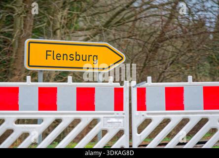 Des barrières portables rayées rouges et blanches bordent une zone de travail, derrière elles un panneau de direction avec une flèche pointe vers la ville nommée Flensburg sur t Banque D'Images