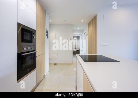 Appartement contemporain vue sur le couloir de la cuisine avec appareils encastrés et surfaces blanches propres Banque D'Images