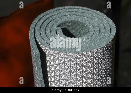 Coussin de couchage en argent roulé pour le camping apporte confort sur une aventure. Ce tapis en mousse léger avec texture thermique fournit une isolation essentielle comme Banque D'Images