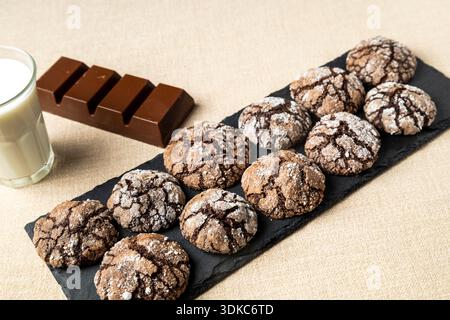 Biscuits froissés au chocolat faits maison enrobés de sucre en poudre sur une planche d'ardoise Banque D'Images