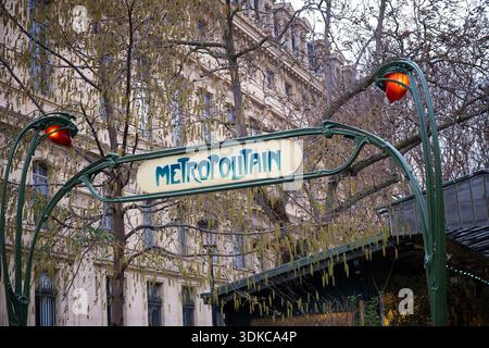 Panneau Lassic Metropolitain avec ferronnerie verte et lampes ambre sur fond de bâtiments historiques et d'arbres printaniers Banque D'Images