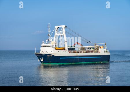 Chalutier en activité en pleine mer près de l'île d'Inis Mor, Galway en Irlande. Grues de pont et treuils prêts pour le déploiement du filet.eau calme avec de légères ondulations, littoral lointain à l'horizon Banque D'Images