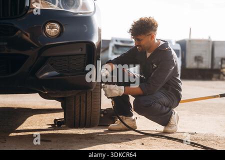 Le mécanicien est avec la voiture à l'extérieur. Banque D'Images