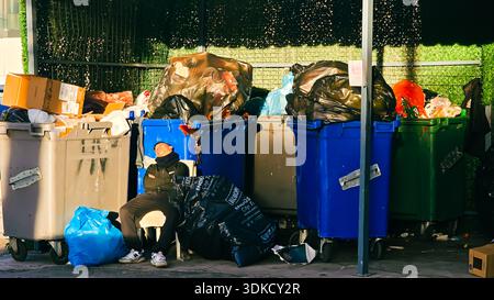 Izmir, Turquie. 30 janvier 2026. Une jeune personne dormant sur une chaise assise devant des poubelles débordantes dans une rue de la ville. La scène capture un moment d'épuisement et de repos au milieu des déchets urbains et de la pollution crédit : İdil Toffolo/Alamy Live News Banque D'Images