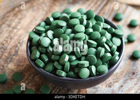 Comprimés d'algues spiruline dans un bol sur une table en bois Banque D'Images