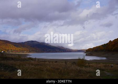 Paysage d'automne du lac Mavrovo entouré de forêt jaune et orange, montrant les couleurs d'automne et la nature paisible dans le parc national de Mavrovo, Macédoine. Banque D'Images