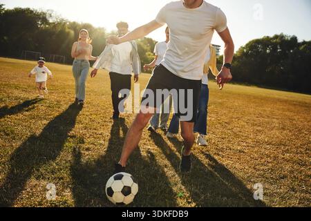 Courir ensemble. Groupe d'amis jouent au football sur le terrain. Banque D'Images