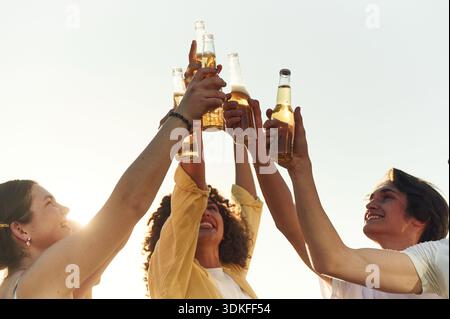 Vue rapprochée d'amis qui encouragent avec des bouteilles de bière à l'extérieur. Banque D'Images