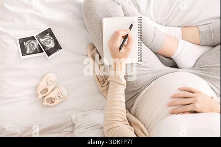Femme enceinte la préparation du travail, assis sur le lit avec un ordinateur portable Banque D'Images